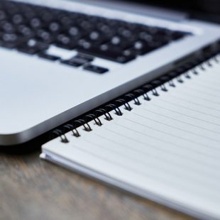 Photographie d'un ordinateur portable à côté d'un cahier