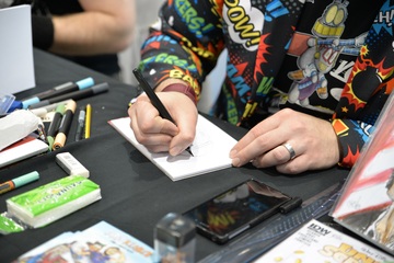 photo des mains d'un artiste en train de dessiner une BD