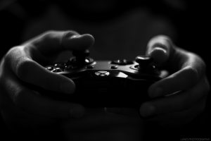 photo en noir et blanc de mains tenant une manette de jeu