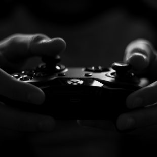 photo en noir et blanc de mains tenant une manette de jeu