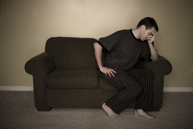 Photographie d'un homme prostré sur un canapé