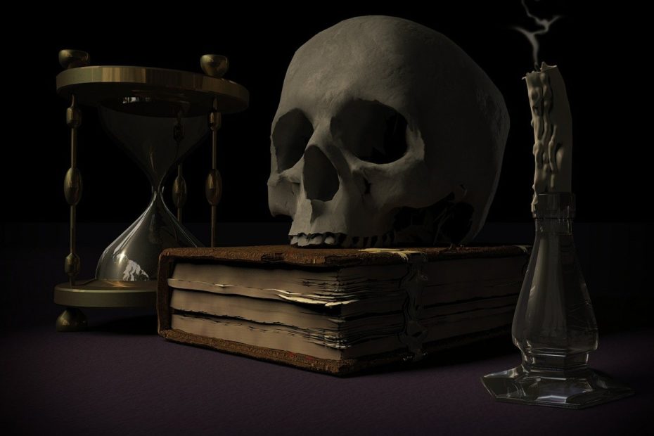 Sablier symbolisant le temps qui passe, un crâne humain posé sur un livre, une bougie éteinte.