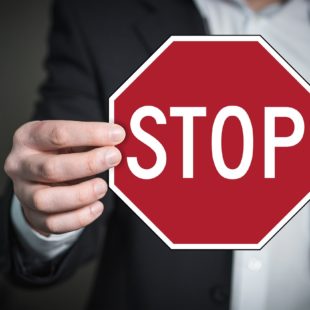 Main d'homme montrant un grand panneau STOP