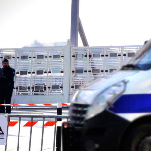 photo d'un car de police devant une barrière et un bâtiment