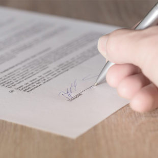 Photographie d'une main qui signe un contrat