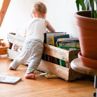 Bébé qui cherche un album dans un bac de livres