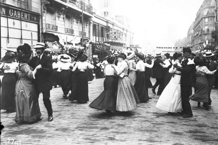 Photographie en noir et blanc lors du Bal du 14 juillet 1912 par l' Agence Rol Hommes et femmes en train de danser dans une rue