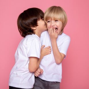 2 enfants riant sur fond rose