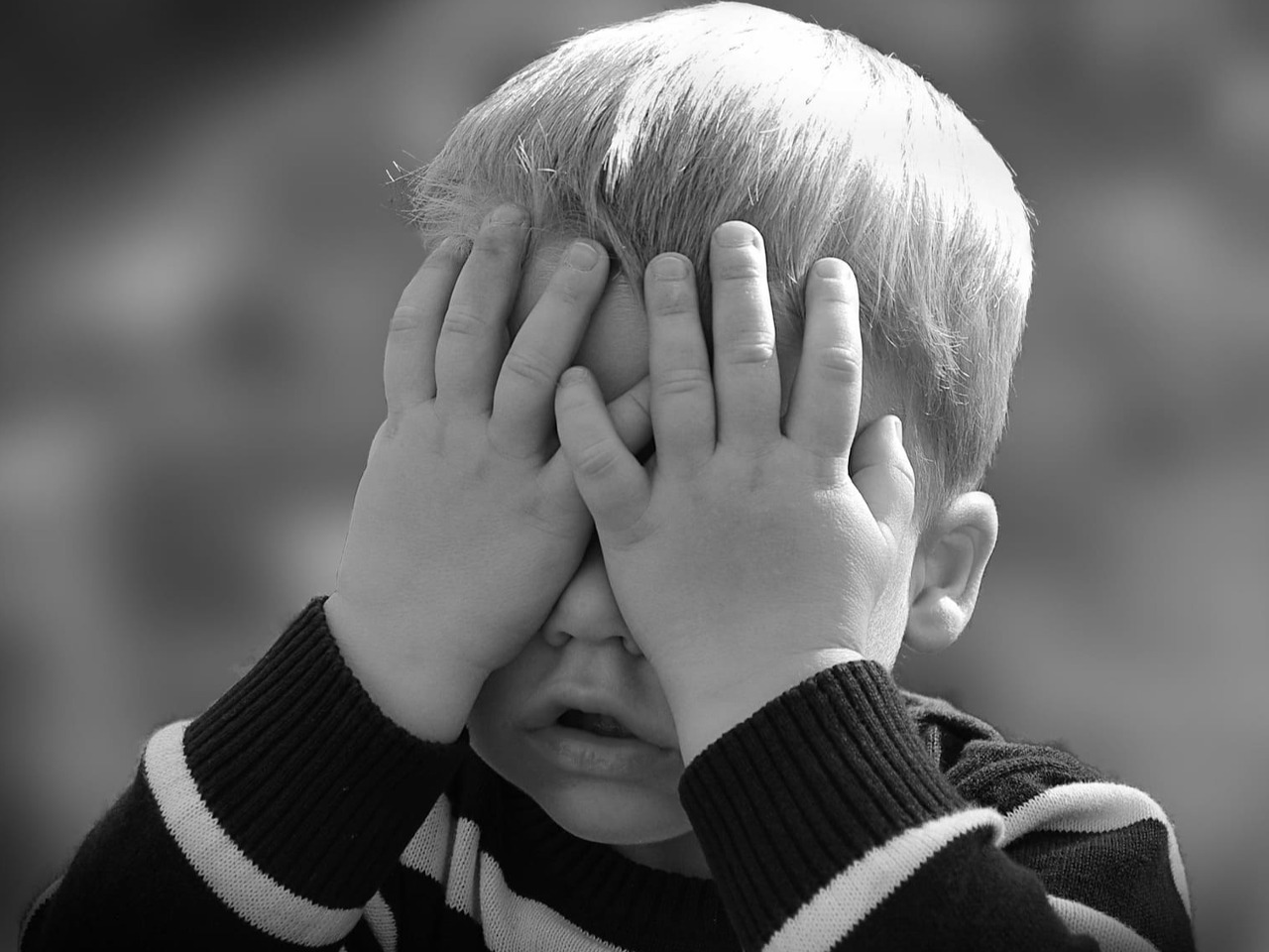 Petit garçon qui se cache les yeux avec ses mains.