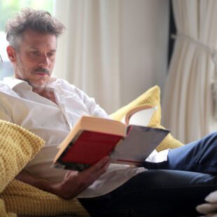 Homme lisant dans un fauteuil avec un personnage miniature lui parlant dans l'oreille à l'aide d'un mégaphone